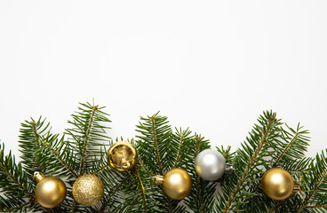 Fir twig and christmas baubles, white background