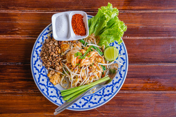 Fried Rice Sticks with Shrimp or Pad Thai Goong Sod with sugar and chilli powder in beautiful dish on wooden table, special Thai food in Thailand