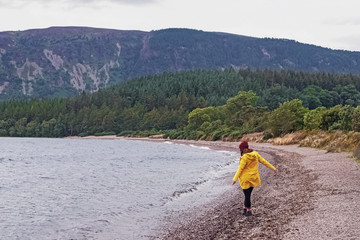 Fototapeta premium Woman in yellow raicoat walking near the lake.