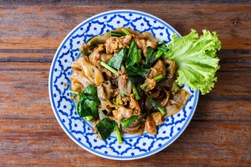 Fried Noodle in Soy Sauce in beautiful dish on wooden table, special Thai food in Thailand