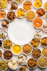 Rangoli of sweets and Farsan/snacks in bowls for Diwali with diya over white background