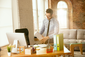 Management. A young businessman moving in the office, getting new work place. Young male office worker while managing after promotion. Looks happy. Business, lifestyle, new life concept. Unpacking.