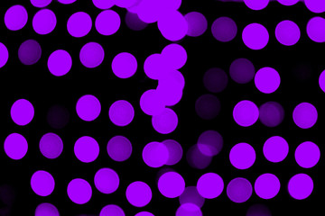 Unfocused abstract purple bokeh on black background. defocused and blurred many round light