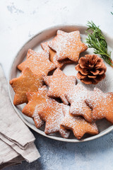 Homemade Christmas New year star shape gingerbread cookies in ceramic plate on old concrete gray vintage background. Top view with space.