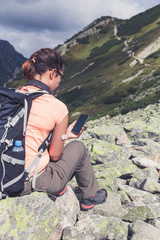 Active life of diabetics, sitting woman looking at mobile phone with checked glucose level from remote sensor mounted on her hand