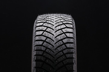 new winter studded tire closeup on black background. a lot of spikes, driving safety in winter on...