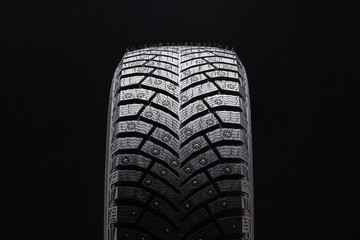new winter studded tire closeup on black background. a lot of spikes, driving safety in winter on ice, new. © Vladimir Razgulyaev