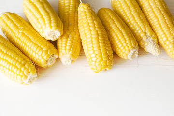 Fresh corn on the cob on white wooden surface