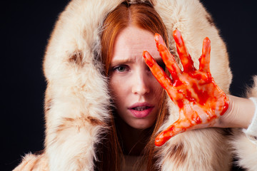 sad redhaired ginger fashion victim woman with blood on her hands wearing natural fur coat and...