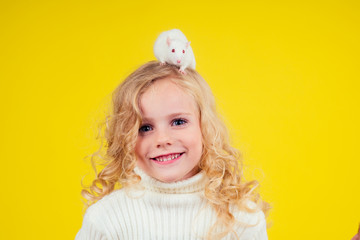 smiling preteen girl with rat on the head in studio yellow background.pet training concept
