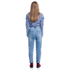 Obraz premium Woman in jeans and blue shirt looking standing on white background isolation, rear view