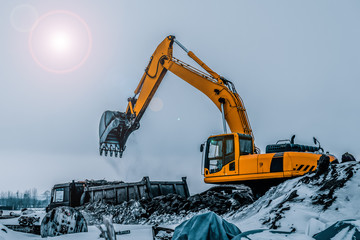Excavator is loading excavation to the truck. Excavators are heavy construction equipment consisting of a boom, dipper or stick , bucket and cab on a rotating platform.