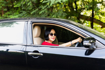 Happy senior woman in sunglasses driving a car.