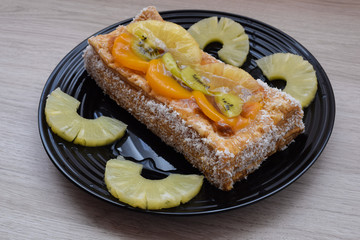 Delicious dessert of puff pastry and fruits on a black plate