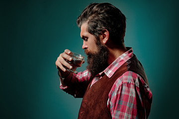 Man Bartender with beard holds glass brandy. Luxury alcohol drink.