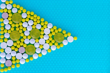 Pills and vitamins in the form of a triangle on a blue background. Medical concept.