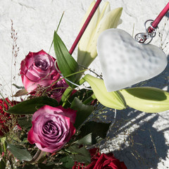 Decorative white heart placed in a flower bouquet surrounded with Deep Purple roses and Lilium Longiflorum flowers.