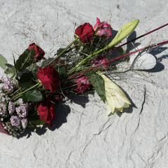 Beautiful arranged flower bouquet with Red Naomi roses, Lilium Longiflorum, Chrysanthemum Santini, Gypsophila and Deep Purple roses. The bouquet is decorated with a white heart at the bottom.