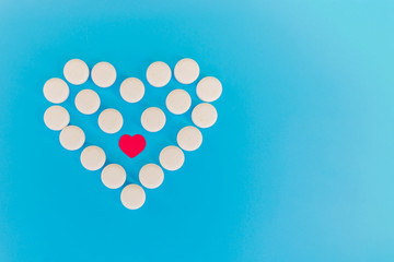 The white heart pills on a blue background with copy space. The concept of a healthy life. Heart disease as arrhythmia or heart failure. Health problem. The impact of the pill on pregnancy.