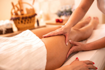Masseuse applying her techniques on a woman’s thigh - obrazy, fototapety, plakaty