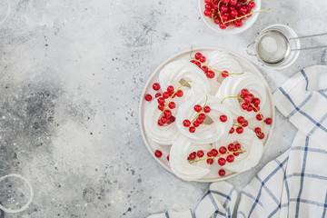 Obraz na płótnie Canvas Meringues in the form of rings with bunches of red currants on a white plate