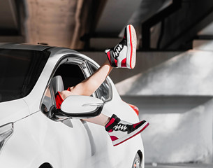 young woman in casual sports wear resting and put legs out of a car.