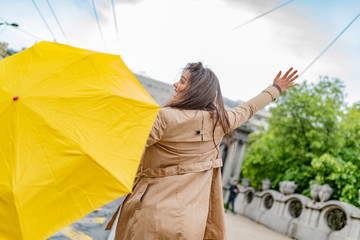 Woman with umbrella catching taxi. Hello taxi. Hailing a Taxi. Young girl with umbrella trying to stop a cab. Woman calling a taxi on a rainy day.