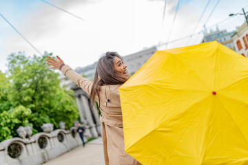 Joyful woman walking in rainy weather. Happy young woman walking with umbrella under the rain. I love it when it's raining! This weather won't get me down