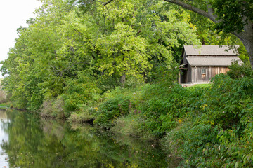 An old, rustic wooden barn along a river among the trees.