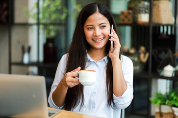 Asian woman in blue shirt working and drink coffee in coffee shop cafe vintage color tone