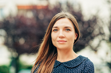 Outdoor portrait of attractive young woman with long brown hair