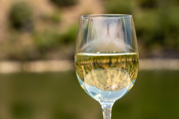 Glass of white wine for tasting on deck of cruise boat on the river in the Douro valley in Portugal