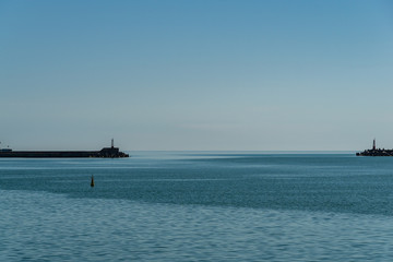 Obraz premium View from shore to water area of seaport. From open sea, port's water area is limited by Breakwaters. Light pointers are installed on extreme parts of breakwaters. Calm Black Sea to very horizon.