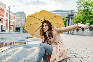 Good mood at any weather. Attractive young smiling woman. She is happy.She used her hand to touch the rain. Who cares if it rains, I've got my umbrella! Happy young woman with umbrella under the rain © Dragana Gordic