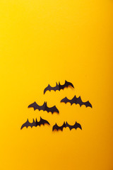 Witch on broom and black paper bats flying on yellow background. Halloween concept. Paper cut style. Top view