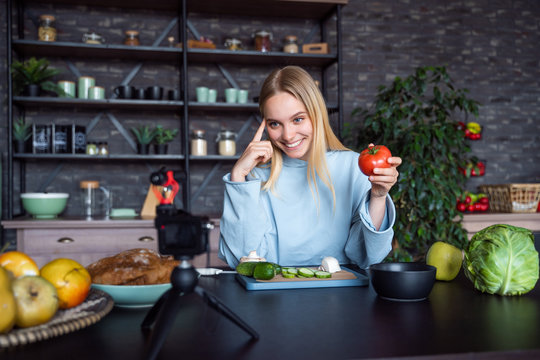 Young beautiful blonde takes on videos as she cooks in the kitchen