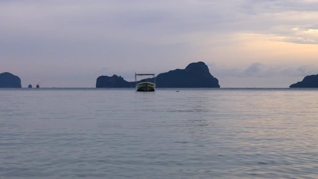 Speedboat floating in the sea, islands and cloudy evening sky in the background. Handheld.