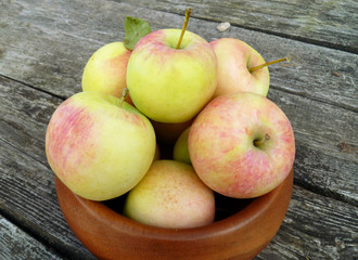 Apples. Bunch of freshly picked green apples with red stripes packed into wooden bowl on old rustic wood background. Close up, selective focus.
