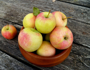 Apples. Bunch of freshly picked green apples with red stripes packed into wooden bowl on old rustic...