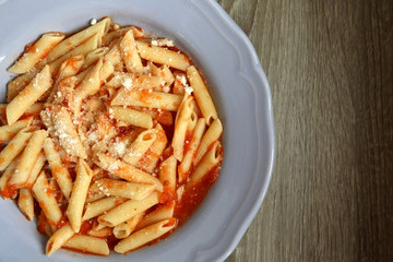 Plate of pasta with homemade tomato sauce. Sprinkling parmesan cheese on top. Flat lay.