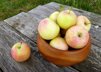 Apples. Bunch of freshly picked green apples with red stripes packed into wooden bowl on old rustic...