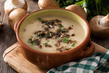 Homemade mushroom soup in bowl on wooden table. 