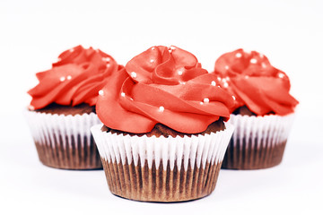 Three delicious cupcakes with icing in trendy coral color on isolated white background. Close-up.