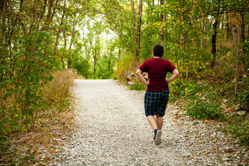 Fototapeta premium Young man walks along a path in a mountain forest.