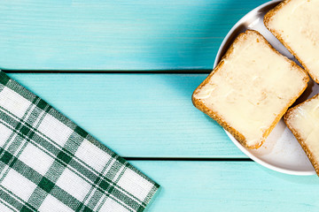 Toasted bread with butter on blue wooden table, top view and copy space image