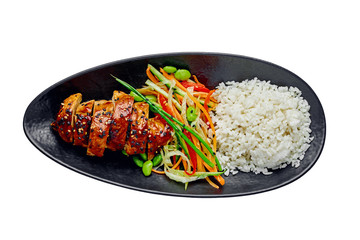 Delicious Asian teriyaki chicken, salad made of cucumber, carrot, ginger, pepper and cabbage, edamame, sesame and rice in a black pottery isolated on white background. Top view, directly above.