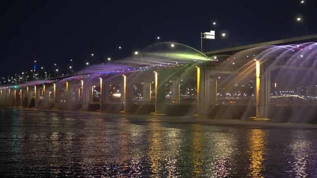 clip of the famous rainbow fountain on the Banpo Bridge in Seoul South Korea at night. From this low angle we see the jets of water, colored light and cars passing on both levels of the bridge