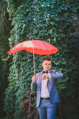 Man with a red umbrella looks at the clock