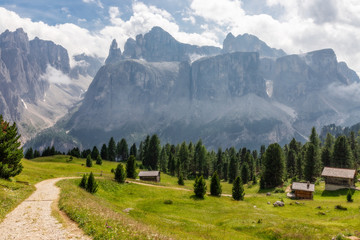 Fototapeta na wymiar Picturesque path on a high alpine meadow surrounded by foggy peaks. Italian Dolomites. Italian Alps, Alto Adige, Colfosco.