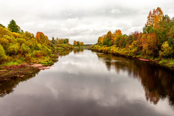 Natural autumn landscape with river shore scene and village view on fall background.
